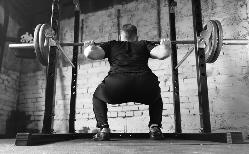 man squatting in power rack