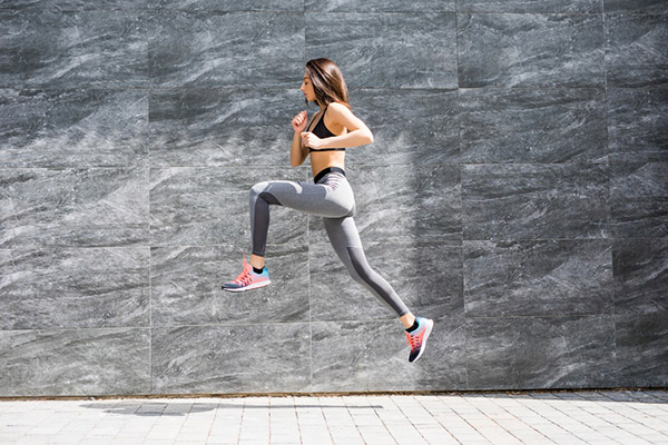 How Running Changes Your Body 4 young woman with fit body jumping running against grey wall