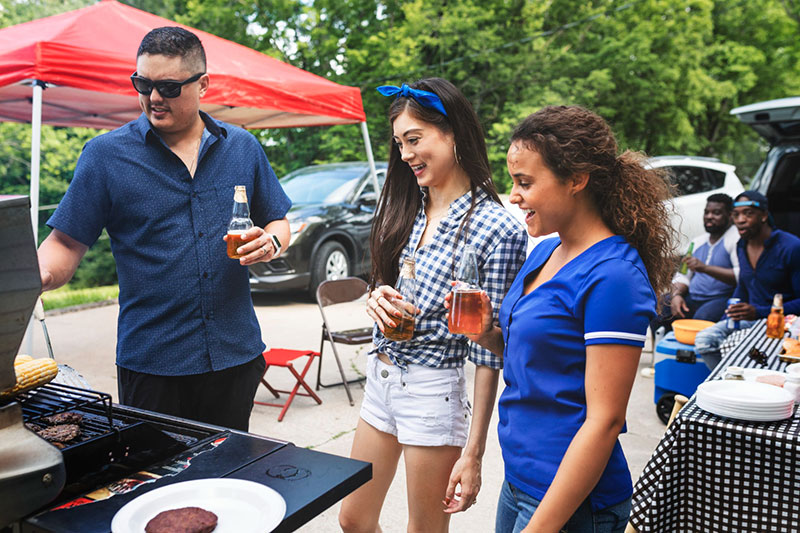 grilling burgers at a tailgate party with tailgate tent