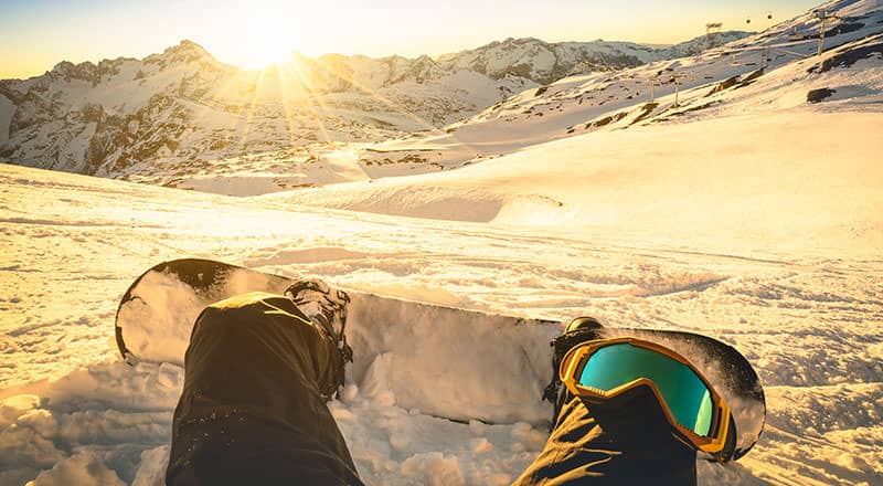 13 Beginner Snowboarding Tips: Advice For First-Timers 4 Snowboarder sitting on relax moment at sunset in french alps ski resort
