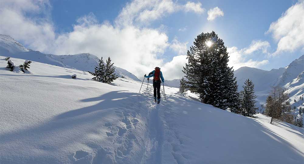 Tips For Your First Backcountry Skiing Trip 1 person backcountry skiing in sun